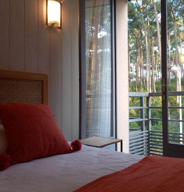 Chambre avec lit double et balcon vue sur la forêt de pins à Biscarrosse Plage dans les Landes